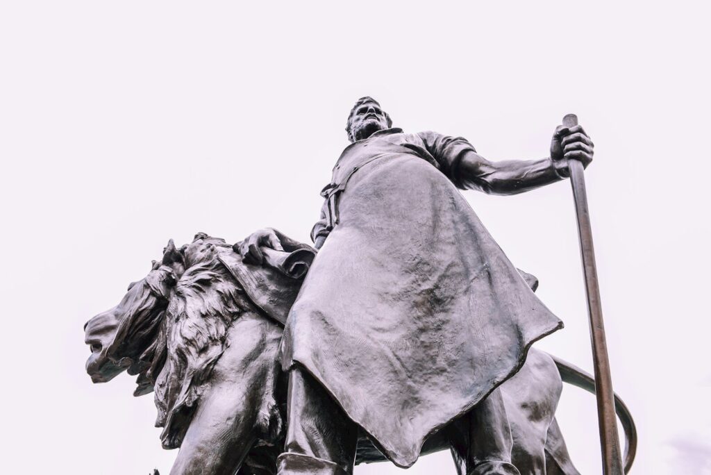low angle photo of man beside lion statue